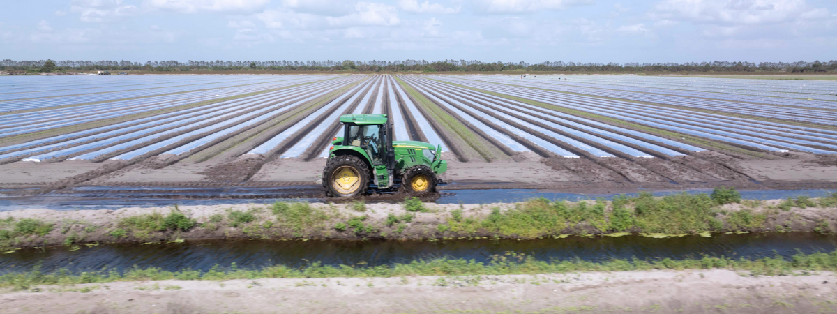 green tractor driving through farmland